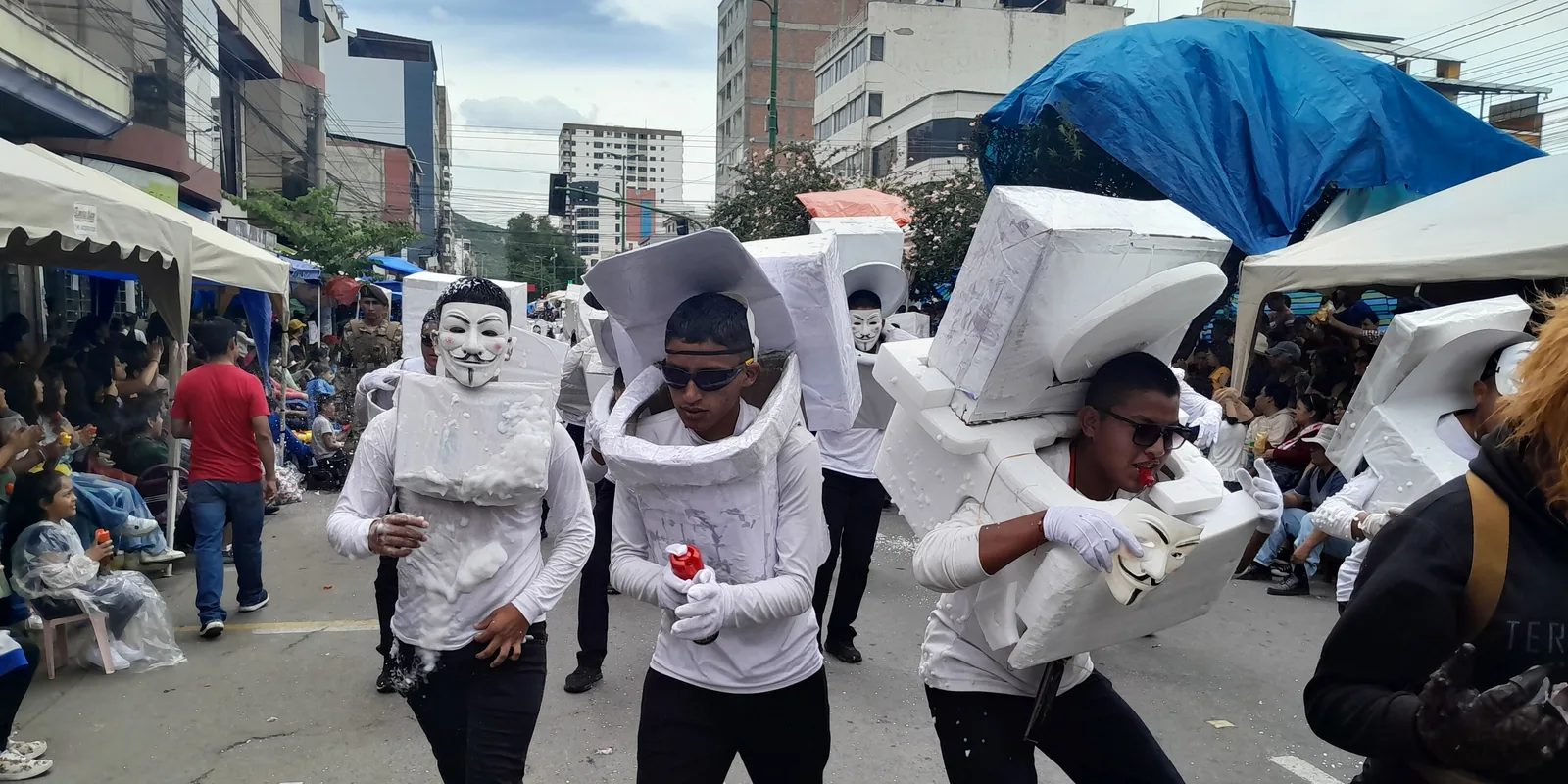 Dancers dressed as Skibidi Toilet characters, wearing toilet costumes and masks, in a street parade in Bolivia